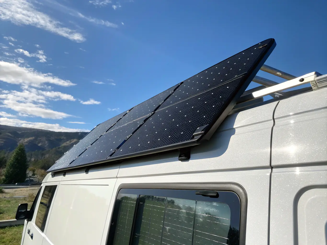A high-quality solar panel mounted on the roof of a van, with a clear blue sky in the background, symbolizing sustainable power solutions for van life.